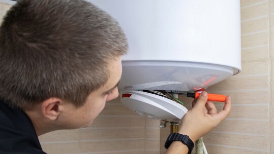 Plumber carrying out hot water system maintenance