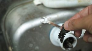 Plumber removing a blockage from a drain